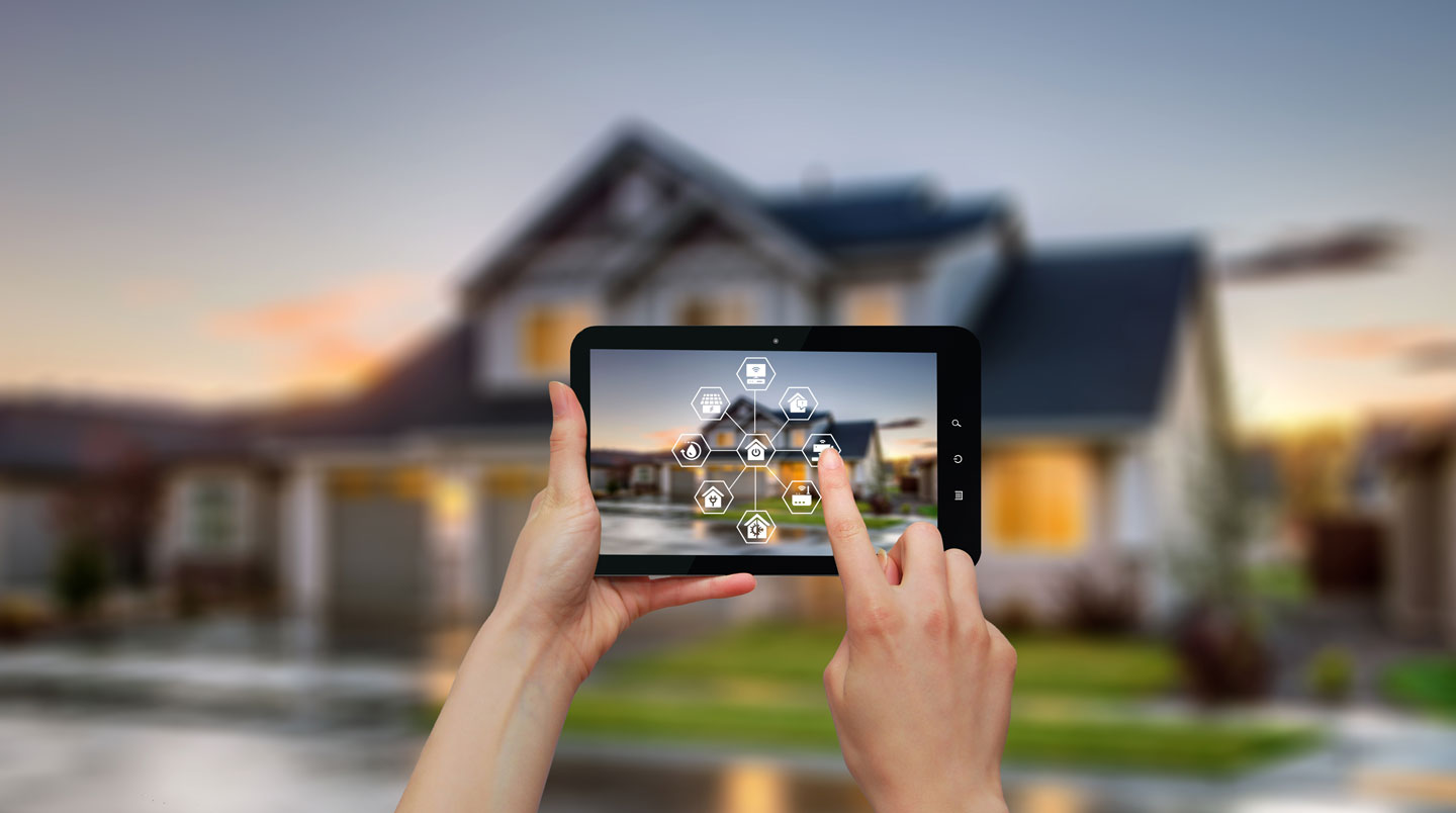 Main tenant un smartphone affichant une application de surveillance résidentielle avec flux vidéo en direct, arrière-plan extérieur estival flou